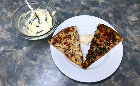 Pizza with bowl of creamy garlic dipping sauce