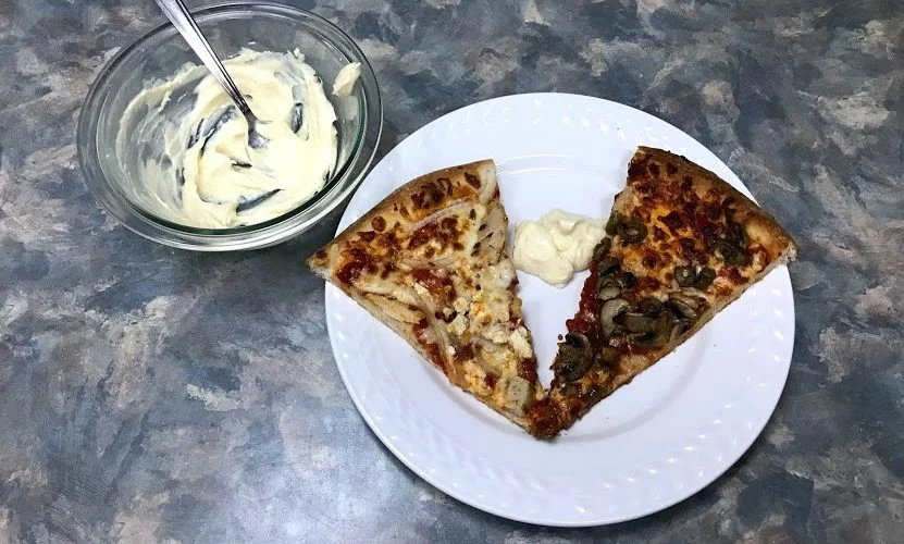 Pizza with bowl of creamy garlic dipping sauce
